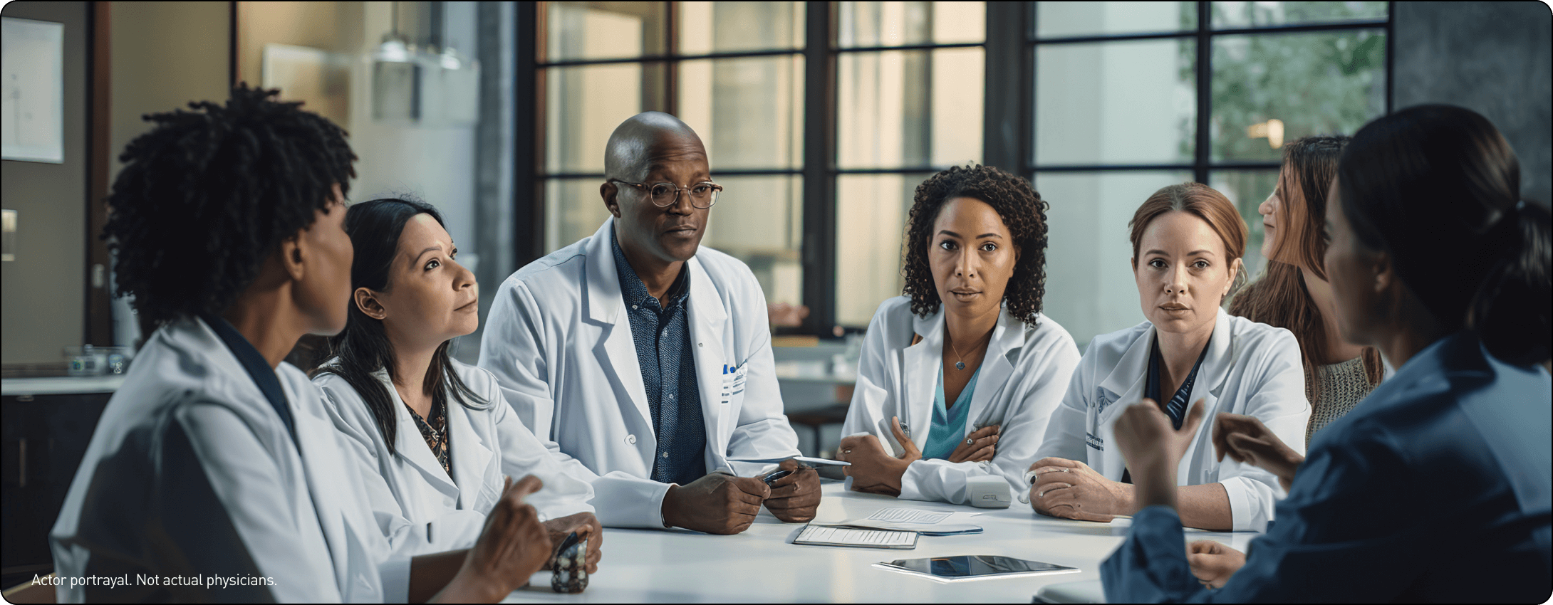 Actor portrayal of a group of doctors having a discussion around a table